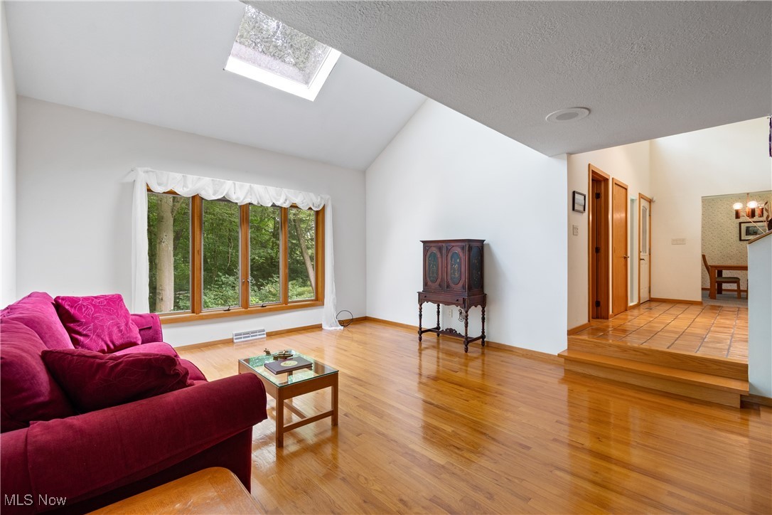 7098 Taylor Road Clinton, OH 44216 - Photo 8 of 39 Living room featuring a notable chandelier, light tile patterned flooring, lofted ceiling with skylight, and a textured ceiling