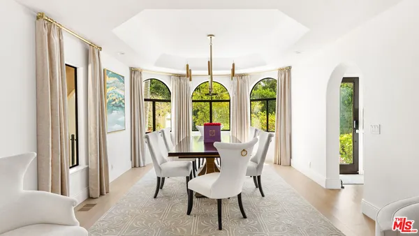 a living room with furniture a rug kitchen view and a large window