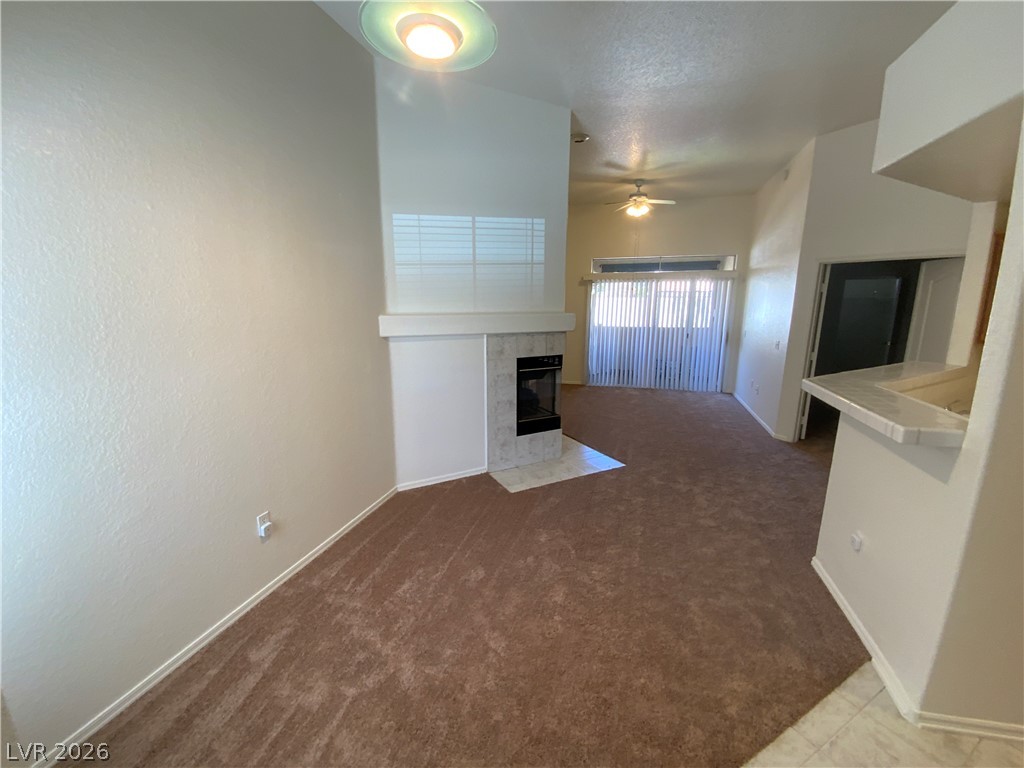 7400 West Flamingo Road, Unit 1039 Las Vegas, NV 89147 - Photo 8 of 40 A cozy living space features an elegant fireplace and a ceiling fan, offering both warmth and comfort.