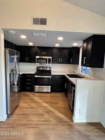 a kitchen with stainless steel appliances kitchen island granite countertop a stove a sink and a refrigerator