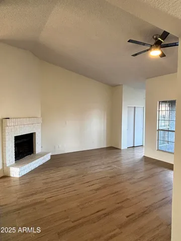 a view of an empty room with wooden floor fireplace and a window