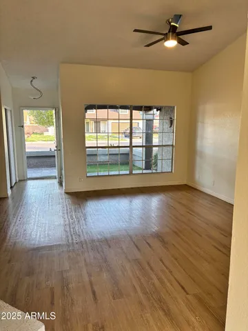 a view of an empty room with wooden floor and a window
