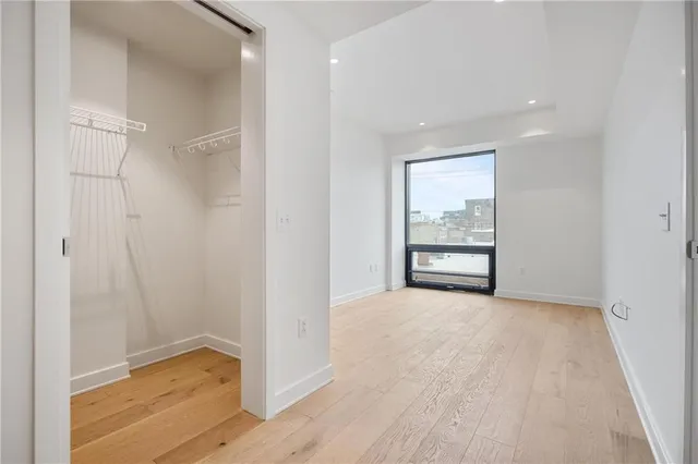 a view of an empty room with a window and wooden floor