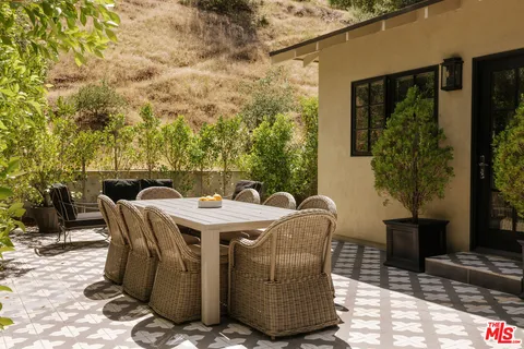 a patio with table and chairs and potted plants