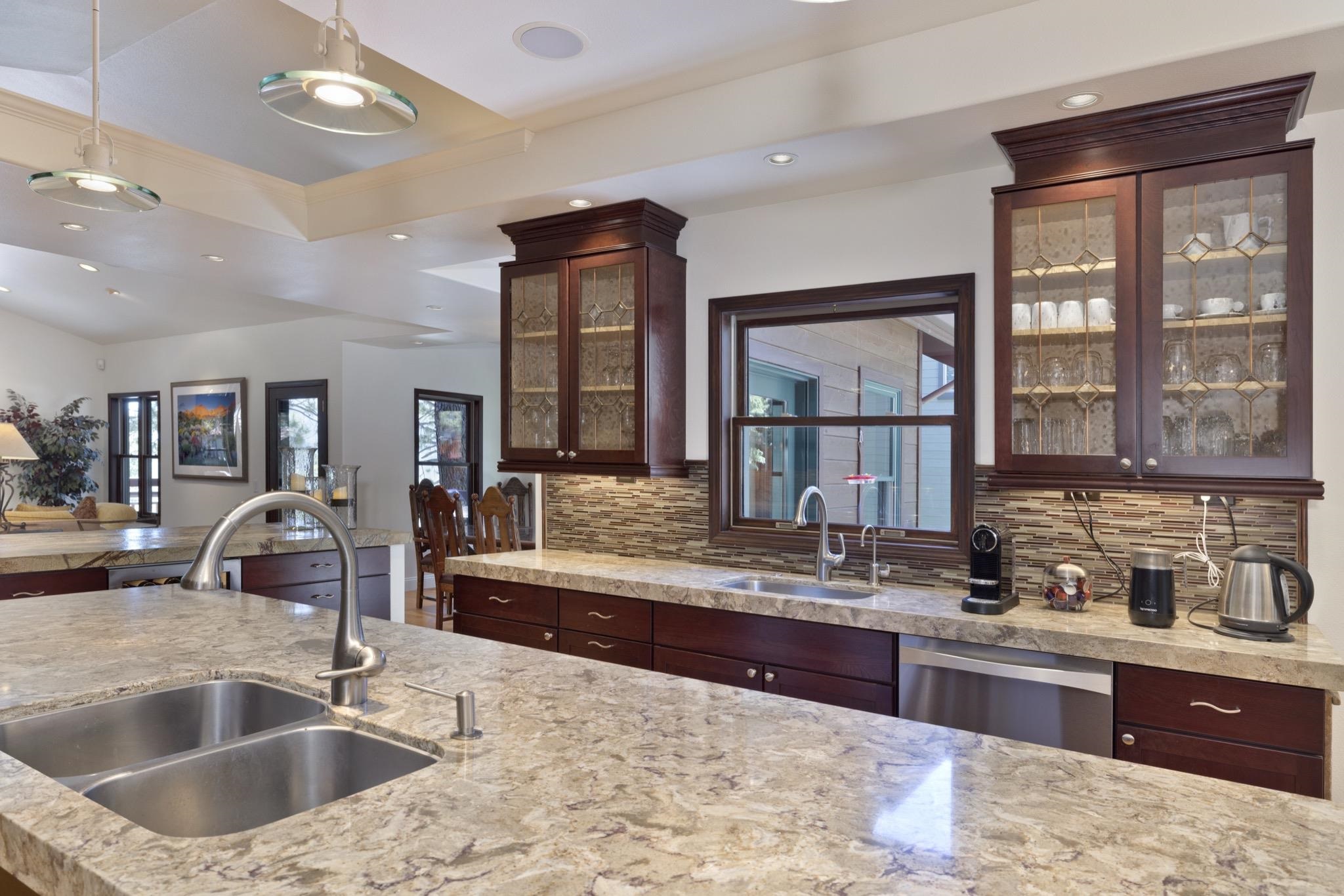 378 Ridge Way Mammoth Lakes, CA 93546 - Photo 15 of 43 Kitchen featuring extensive counter space with a double basin stainless steel sink, dark wood-finish cabinetry, a stone tile backsplash, and recessed and pendant lighting
