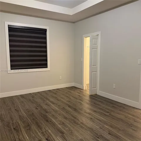 an empty room with wooden floor and a window
