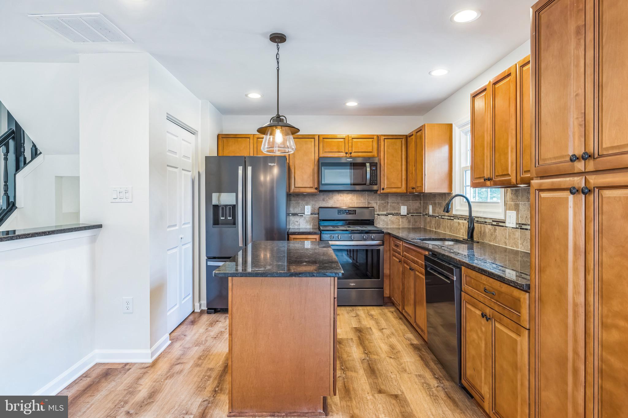 8 Versailles Court Newark, DE 19702 - Photo 12 of 30 a kitchen with stainless steel appliances granite countertop a refrigerator a sink dishwasher a stove and a dining table with wooden floor