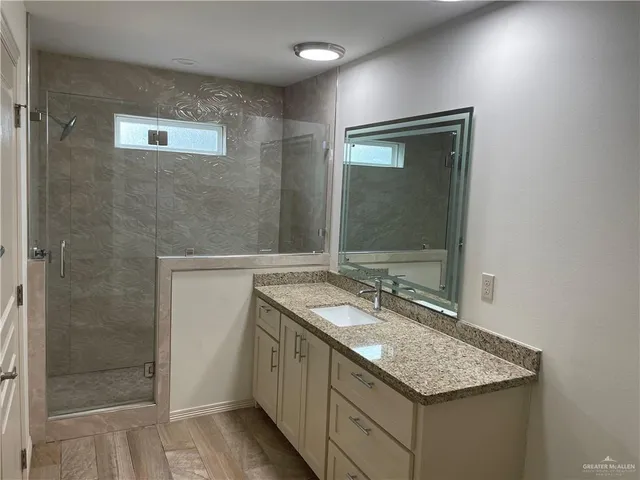a bathroom with a granite countertop sink a mirror and shower