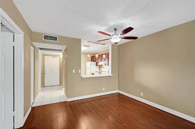 a view of an empty room with window and wooden floor