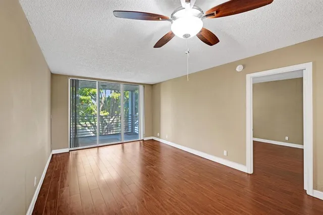 an empty room with wooden floor fan and windows