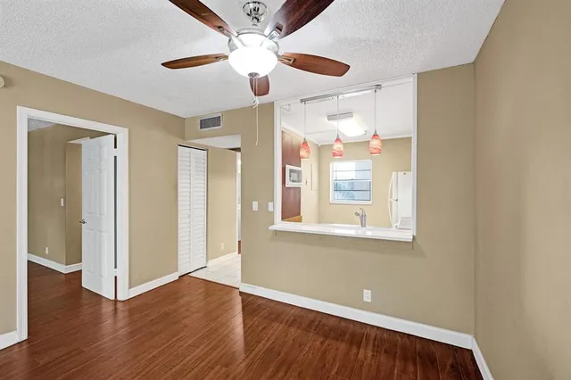 a view of an empty room with a window and wooden floor