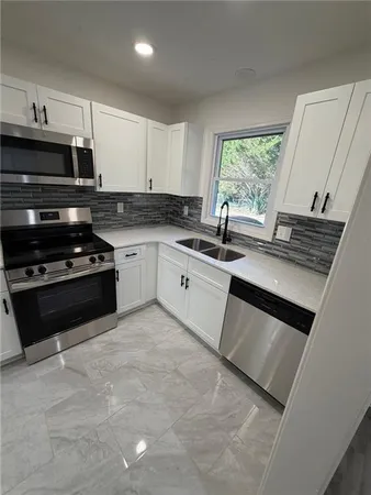 a kitchen with stainless steel appliances granite countertop a stove a sink and a microwave