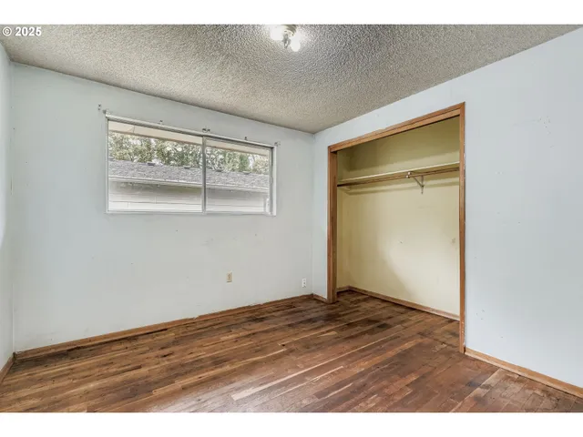 an empty room with wooden floor closet and windows