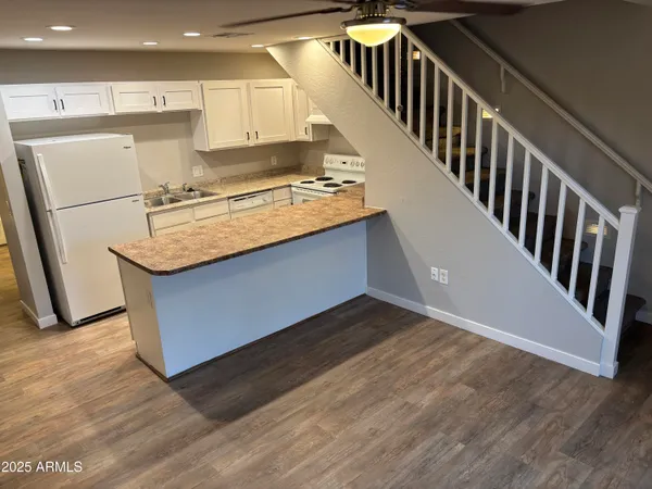 a kitchen with stainless steel appliances granite countertop a refrigerator a stove a sink and white cabinets with wooden floor