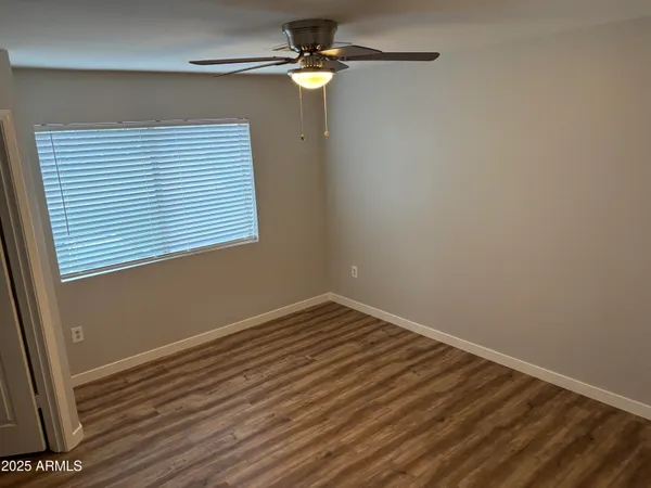 a view of a room with wooden floor and a ceiling fan