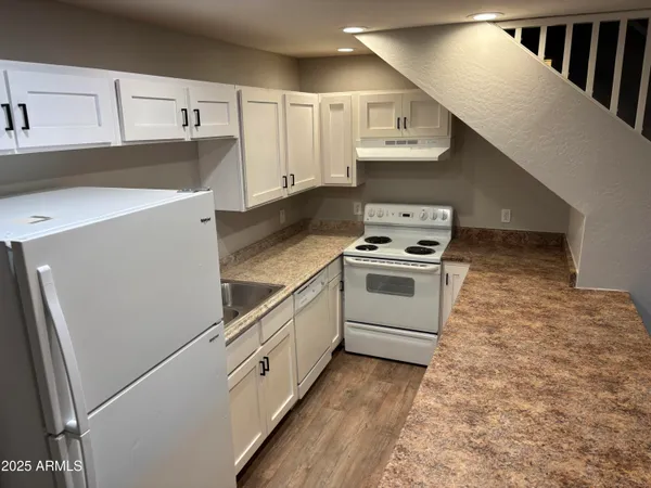a kitchen with granite countertop white cabinets and white appliances