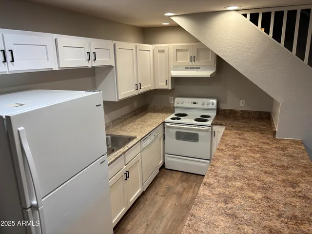 a kitchen with granite countertop white cabinets and white appliances