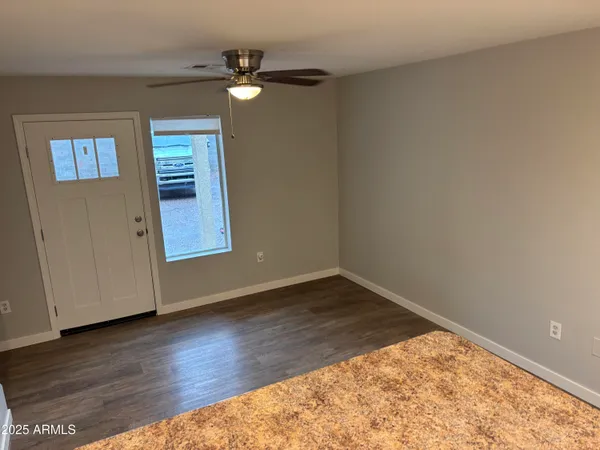 an empty room with wooden floor fan and windows