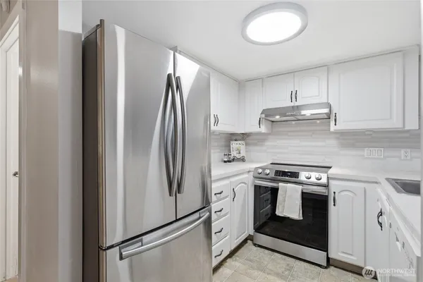 a kitchen with stainless steel appliances granite countertop a refrigerator a stove and a sink