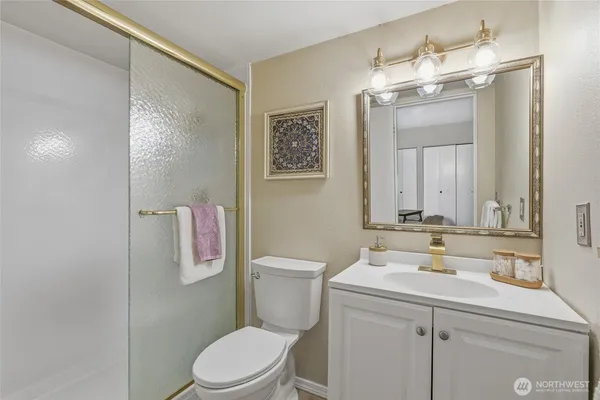a bathroom with a sink a toilet a mirror and shower