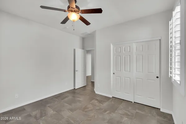 an empty room with windows and fan