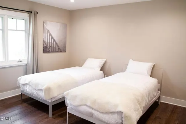 a bedroom with two beds and wooden floor