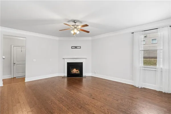 an empty room with wooden floor a fireplace and windows