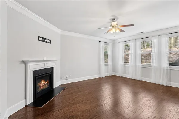a view of an empty room with wooden floor fireplace and a window