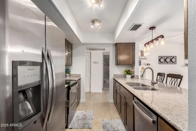 a kitchen with stainless steel appliances granite countertop a sink a stove and a refrigerator