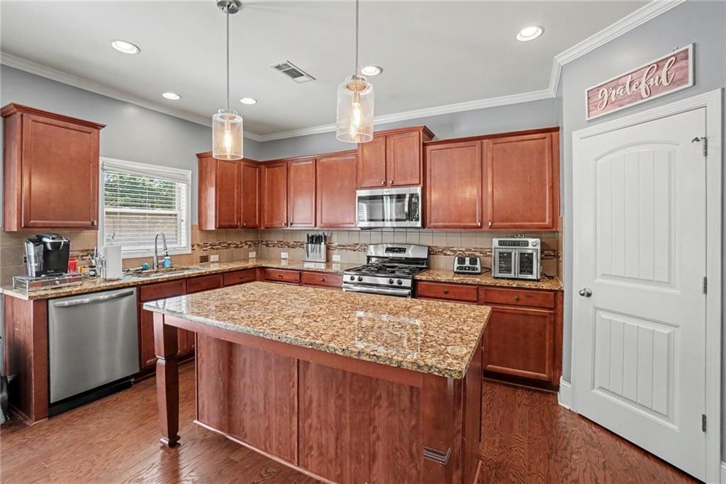 566 Olympic Way Acworth, GA 30102 - Photo 9 of 38 a kitchen with stainless steel appliances granite countertop a refrigerator a sink dishwasher a stove with wooden cabinets and wooden floor