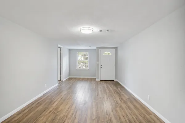 an empty room with wooden floor and windows