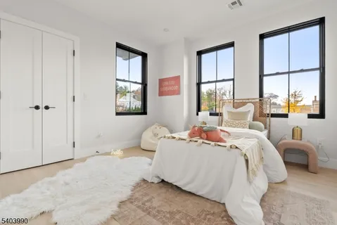 a bedroom with a bed wooden floor and two window
