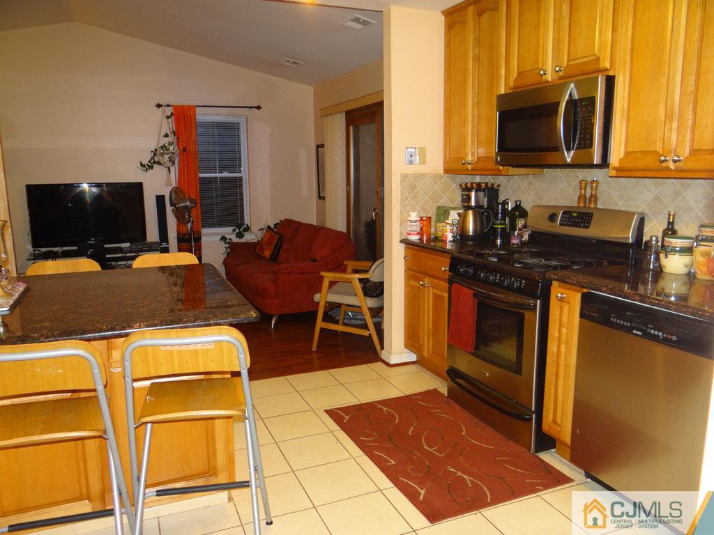 92 Woodbury Road Edison, NJ 08820 - Photo 4 of 16 a kitchen with stainless steel appliances granite countertop a stove top oven a sink dishwasher and a microwave oven with the view of living room