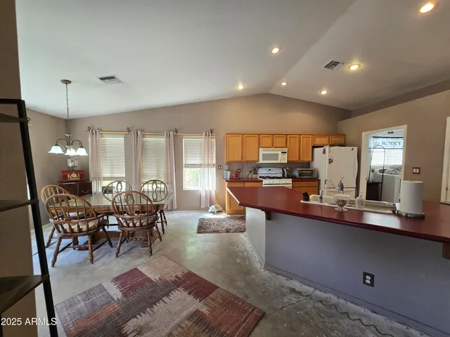 a large dining hall with stainless steel appliances granite countertop a dining table and chairs