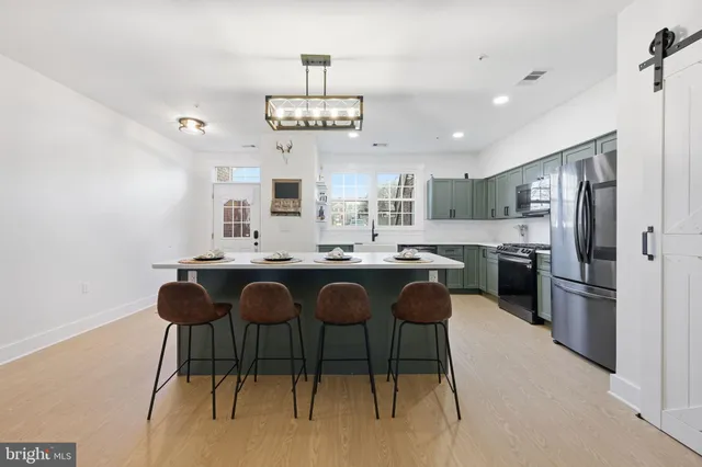 a kitchen with stainless steel appliances granite countertop a sink a stove a refrigerator and island with wooden floor