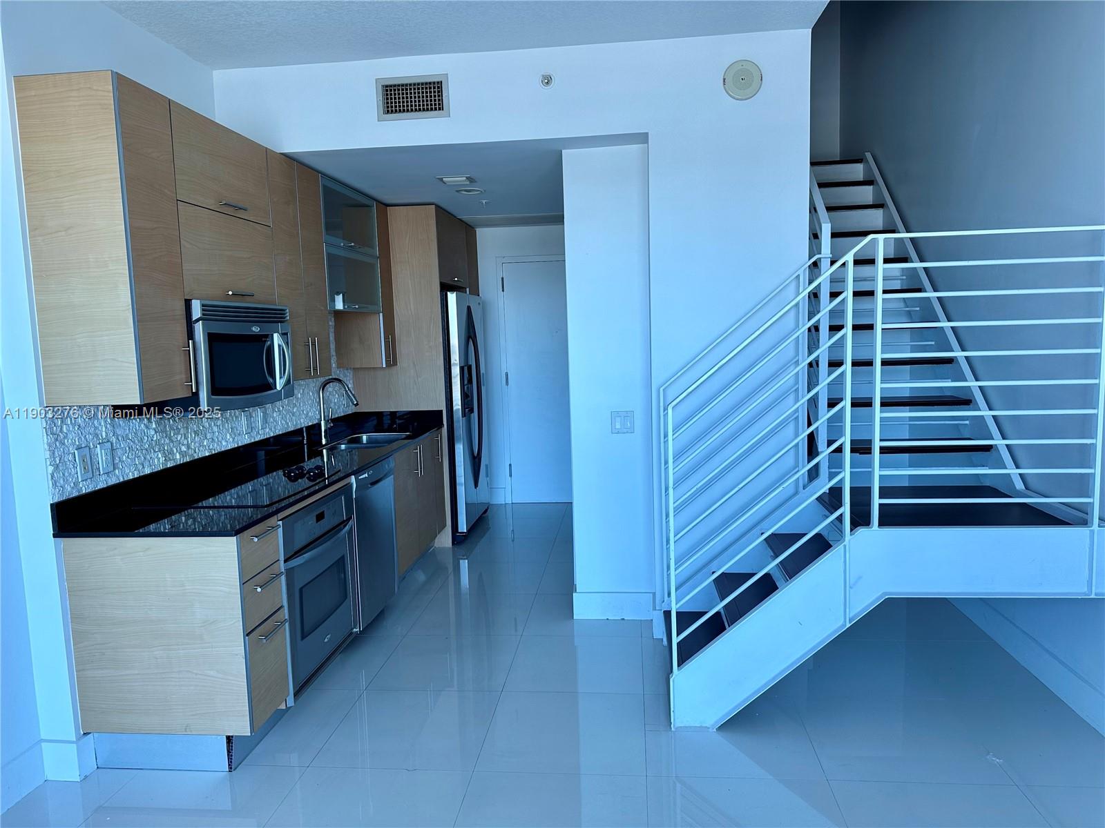 60 Southwest 13th Street, Unit 2213 Miami, FL 33130 - Photo 5 of 19 a kitchen with kitchen island wooden cabinets and stainless steel appliances