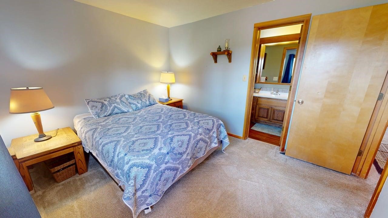 91200 Ryan Gulch Road, Unit 213 Silverthorne, CO 80498 - Photo 14 of 33 a bedroom with a bed and a lamp on dresser