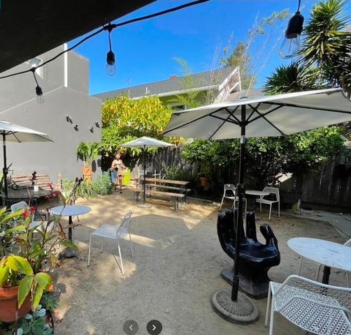 a backyard of a house with table and chairs under an umbrella