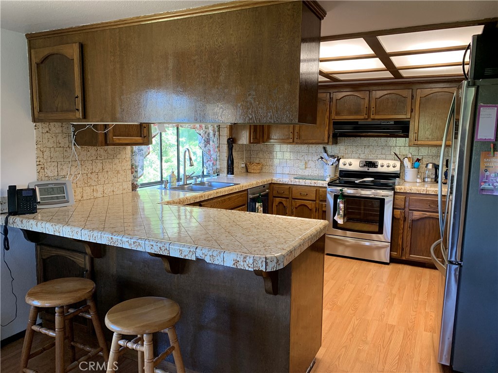18683 Morgan Valley Road Lower Lake, CA 95457 - Photo 9 of 16 a kitchen with stainless steel appliances granite countertop a sink a stove and chairs