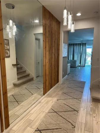 a view of a hallway with wooden floor and chandelier