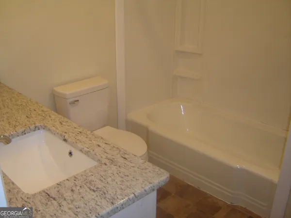 a bathroom with a granite countertop sink and a toilet