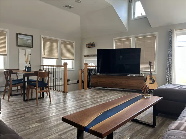 a living room with furniture kitchen view and a wooden floor