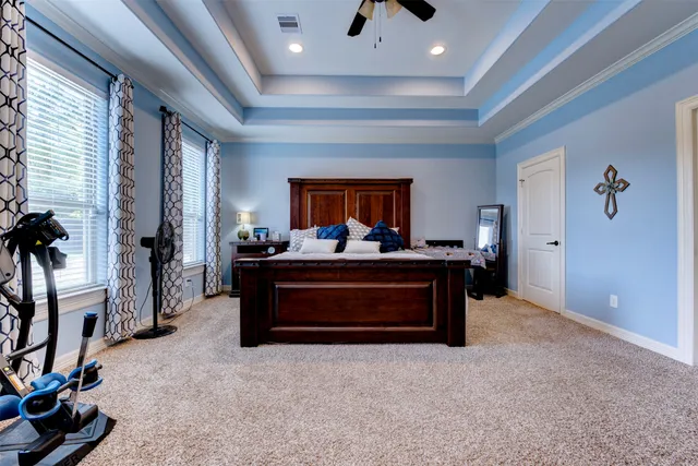 a spacious bedroom with a bed a flat screen tv and a couch
