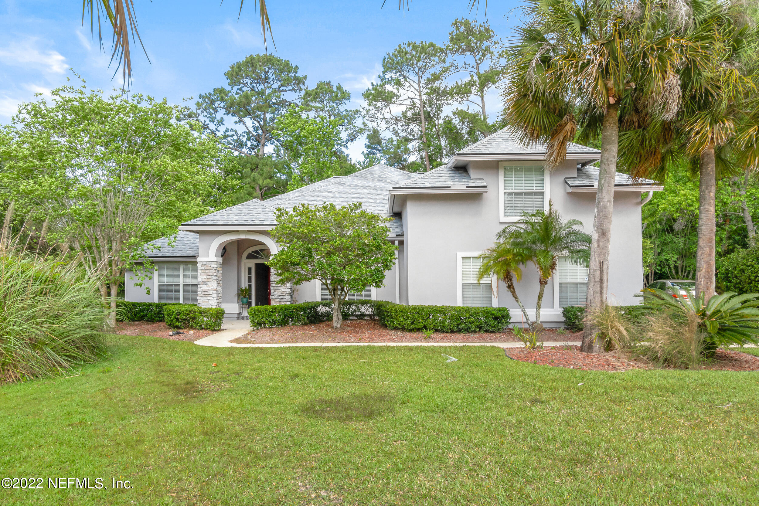 a front view of a house with a yard and potted plants