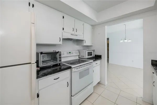 a kitchen with granite countertop white cabinets and white appliances
