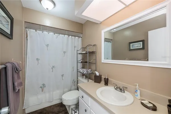 a bathroom with a granite countertop toilet a mirror and shower