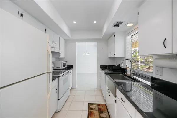 a kitchen with granite countertop a sink stove and refrigerator