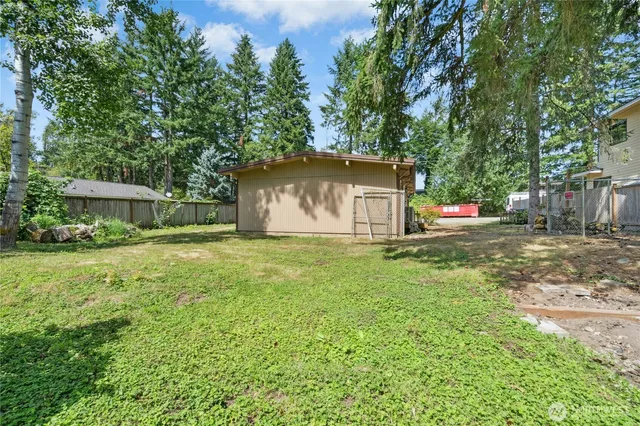 a view of backyard with small cabin and wooden fence