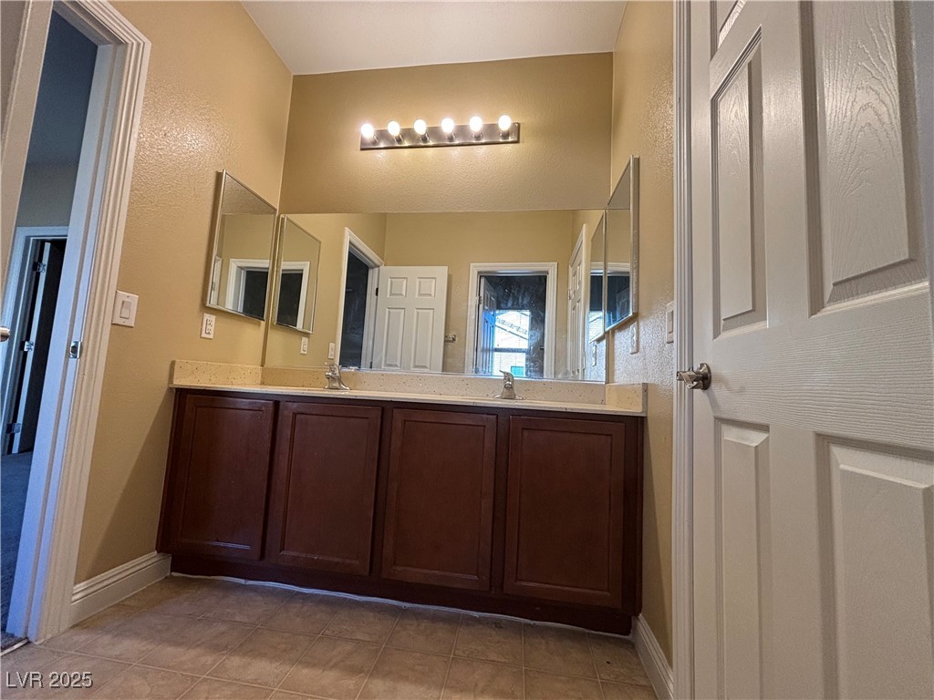 9473 Alma Ridge Avenue Las Vegas, NV 89178 - Photo 16 of 35 Full bath featuring double vanity, light tile patterned floors, and a textured wall