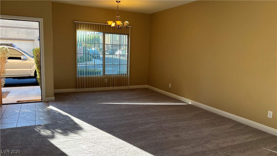 9473 Alma Ridge Avenue Las Vegas, NV 89178 - Photo 9 of 35 Empty room with dark carpet, a chandelier, and dark tile patterned floors